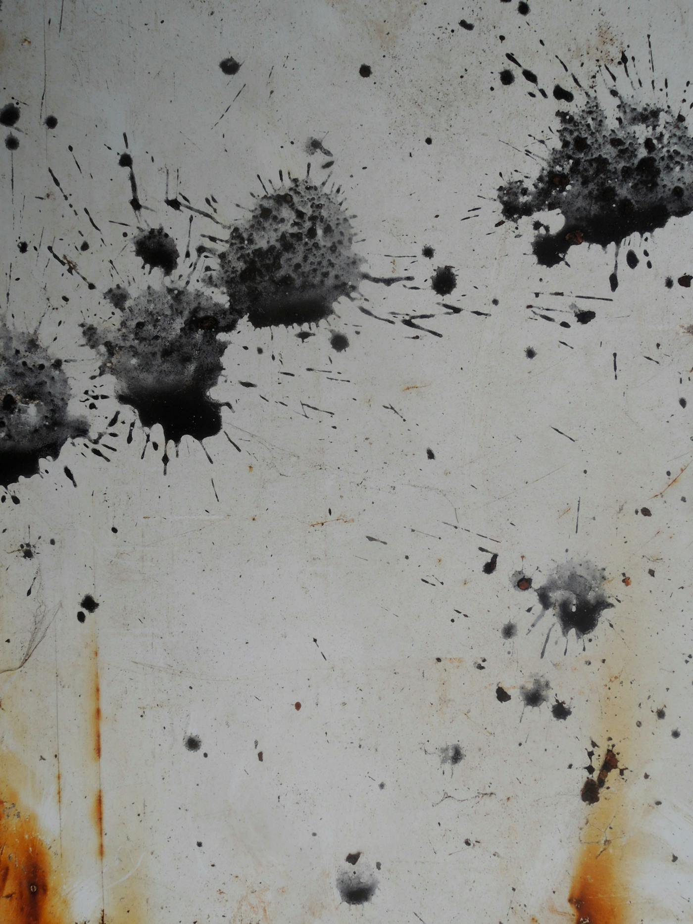 Weathered metal surface with paint splatter and rust